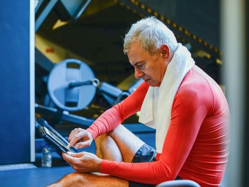 Man in athletic wear reviewing his workout plan on a tablet.